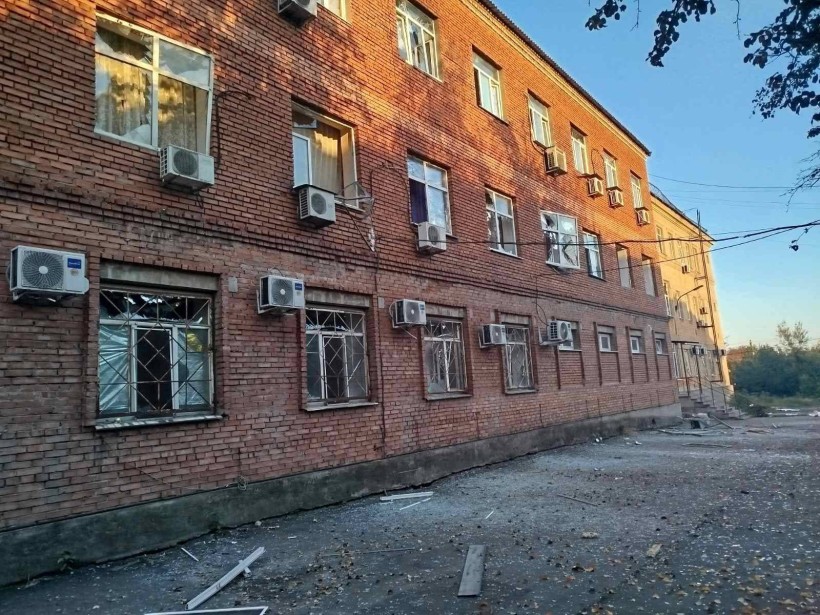 Цегляна будівля з вибитими після обстрілу вікнами