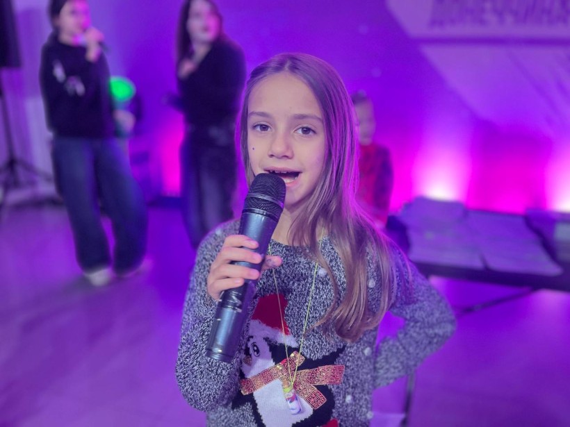 Дівчинка співає з мікрофоном на музичному занятті