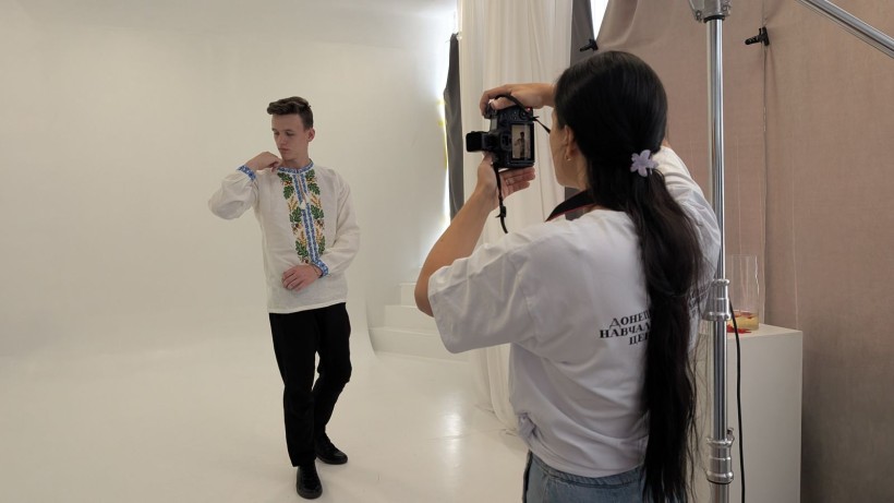Фотограф знімає юнака у білій вишиванці