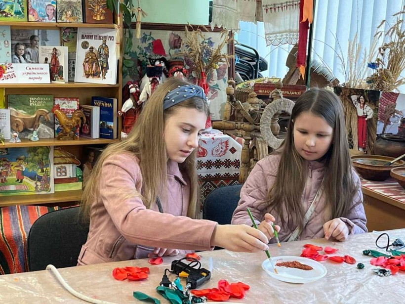 Дівчата декорують пелюстки маків, використовуючи пензлі та блискітки