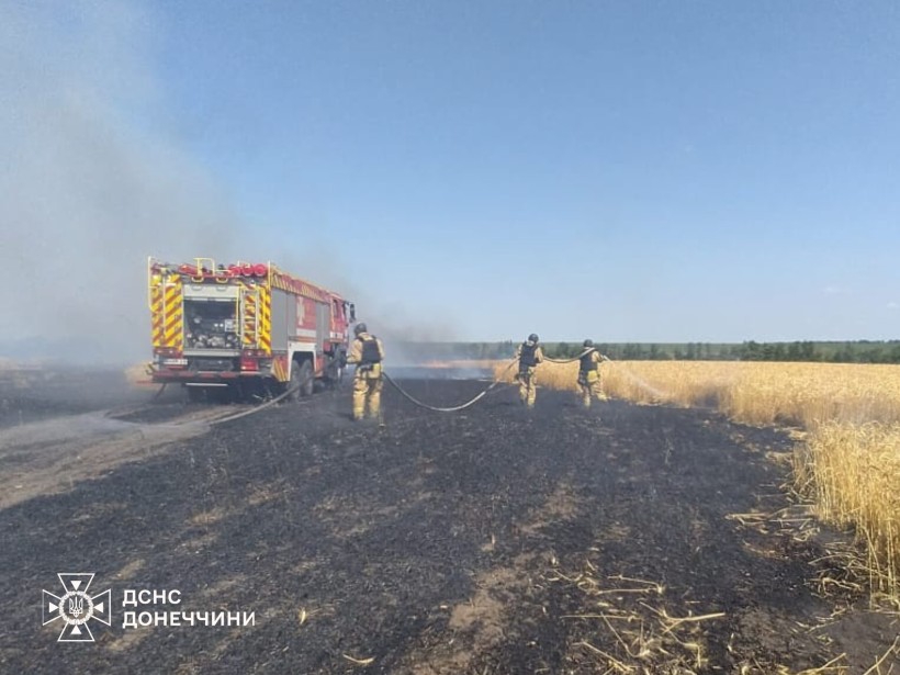Рятувальники гасять пожежу на полях з пшеницею після ворожого обстрілу.