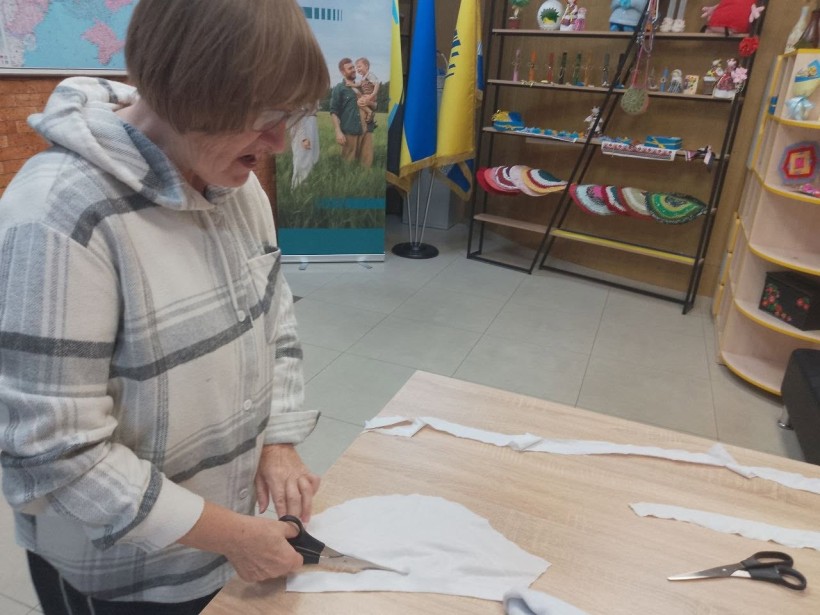 Жінки нарізають білу тканину для маскувальних сіток