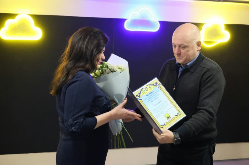 Юрій Вінокуров тримає почесну грамоту, яку вручає працівниці ЖКГ.