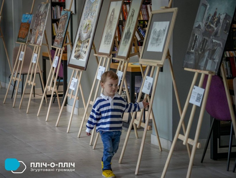 Різні картина на різні теми, біля експозиції ходить маленький хлопчик, який з веселим настроєм відвідує виставку