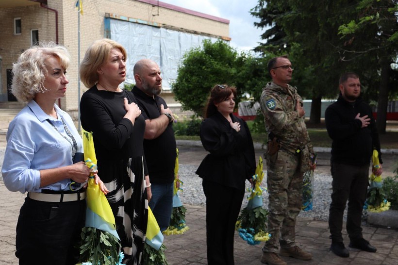Група людей вшановує пам'ять загиблих захисників хвилиною мовчання