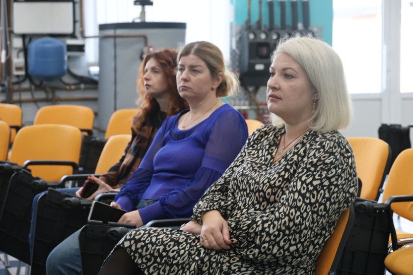 Учасники зустрічі. Жінки сидять на помаранчевих кріслах.