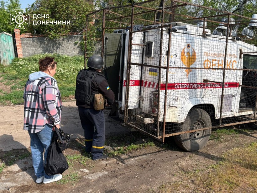 Рятувальник вантажить речі жінки у евакуаційну автівку
