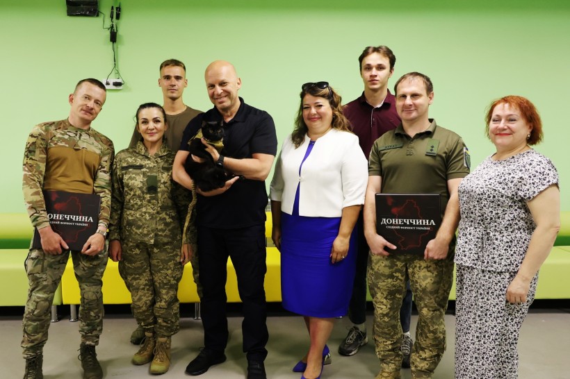 Голова Донеччини Вадим Філашкін разом з учасниками проєкту «Моя Донеччина. Мій дім. Моя фортеця». Вадим Філашкін тримає бойового кота чорного кольору. Двоє військових тримають у руках книгу про Донеччину
