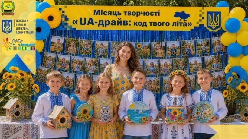 Банер місяця творчості «UA-драйв: код твого літа»: педагог і діти з творчими виробами на святково оформленій фотозоні.