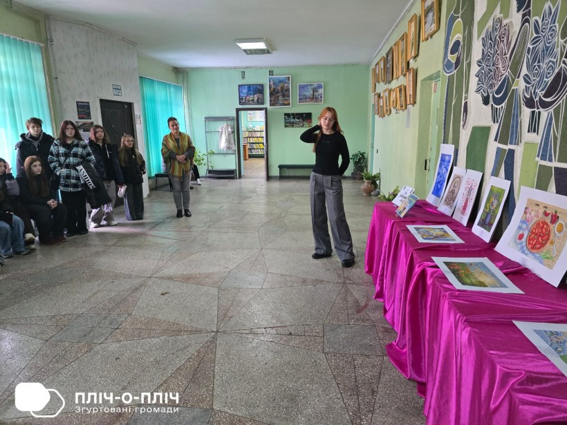 Юна художниця розповідає гостям виставки про свої картини