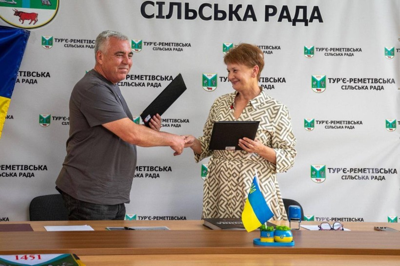 Керівник Тур'є-Реметівської громади Ужгородського району Закарпатської області Надія Девіцька та начальник Миколаївської міської військової адміністрації Краматорського району Донецької області Володимир Проскунін. Тиснуть руки та обмінюються документами.