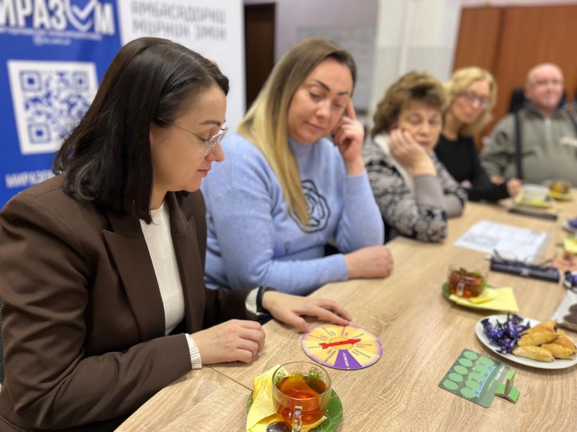 Жінки сидять за столом та грають у гру про Донеччину