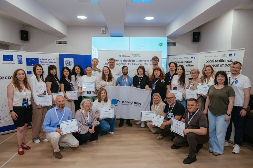 Спільне фото учасників зустрічі з прапором "Пліч-о-пліч: згуртовані громади"