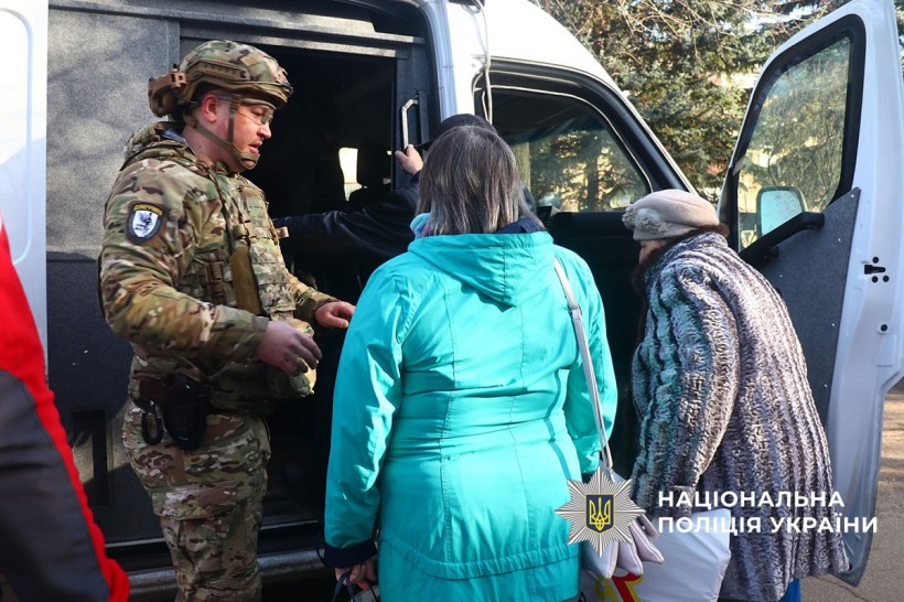 Дві літні жінки сідають до евакуаційного автомобіля, їм допомагає поліцейський