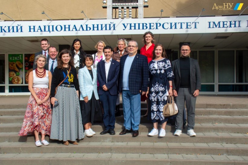 Делегація  членів Парламенту Сполученого Королівства Великої Британії та Північної Ірландії з їх радниками спільно з представниками Донецького національного університету імені Василя Стуса на фоні релокованого головного корпусу.