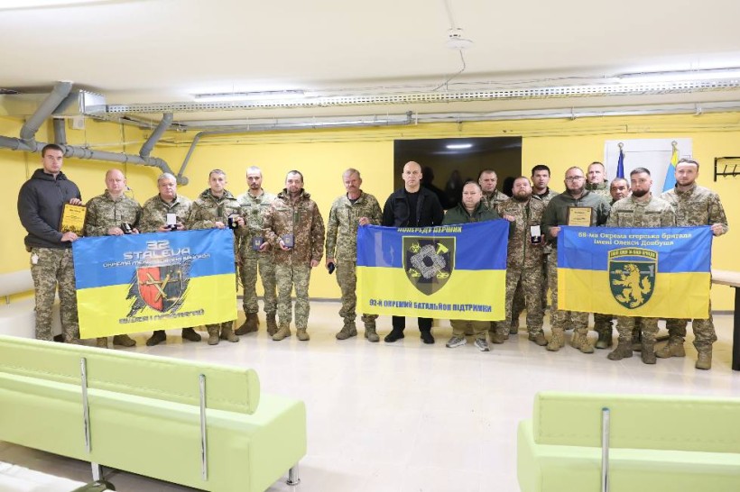 Вадим Філашкін разом з бійцями тримають прапори підрозділів та нагороди