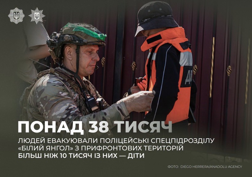 Поліцейський вдягає на дитину помаранчевий бронежилет