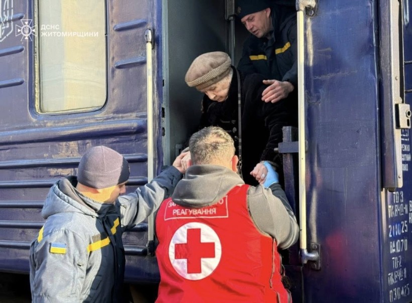 Представники гуманітарних організацій, ДСНС та інших служб допомагають літній людині вийти з евакуаційного потяга