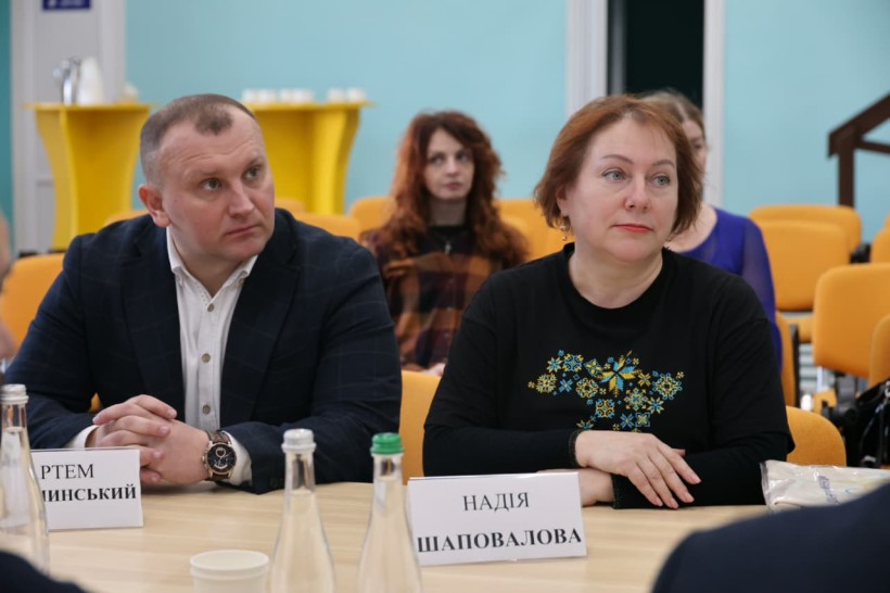 Учасники зустрічі. За столом сидить чоловік та жінка які уважно слухають.