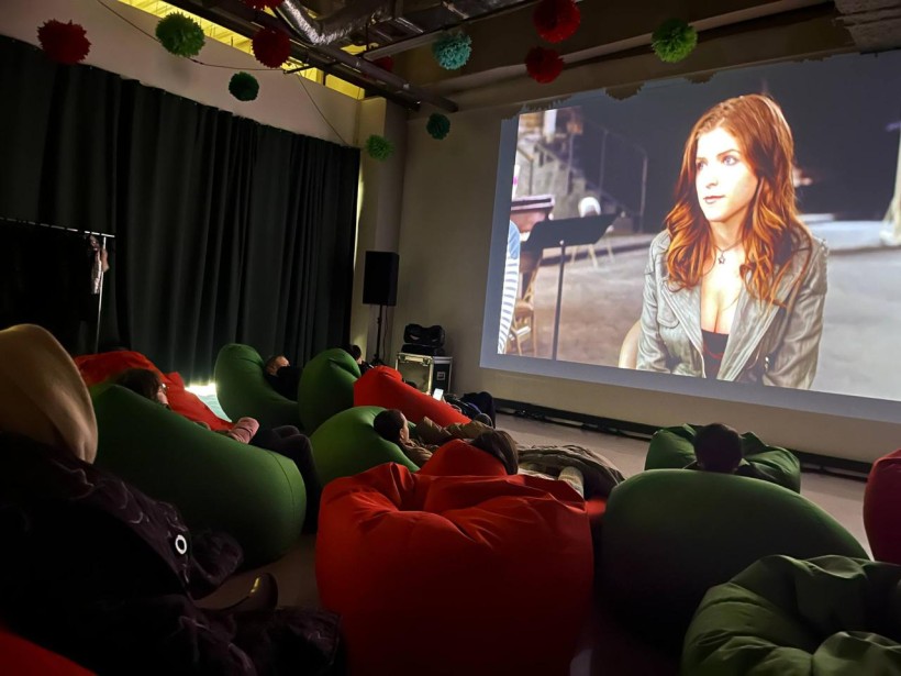 Глядачі на м’яких кріслах дивляться фільм на кінопроєкторі