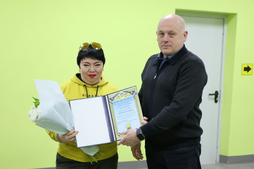 Юрій Винокуров та працівниця ЖКГ, жінка в руках тримає квіти та почесну грамоту.