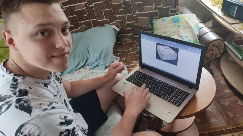 Хлопець працює за ноутбуком удома під час Обласної екологічної експедиції, вивчаючи тему зображеного намета.