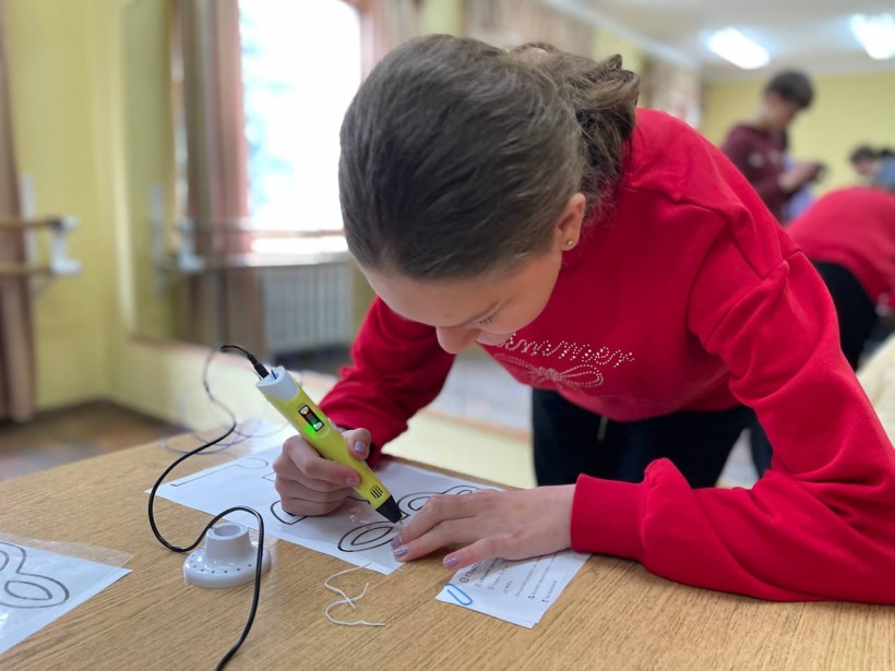 Дівчинка малює 3Д ручкою на аркуші паперу