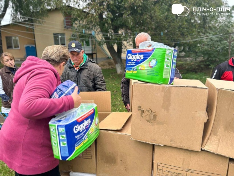 Передача памперсів від благодійників до Будинку ветеранів. Жінки та чоловіки розбирають коробки.