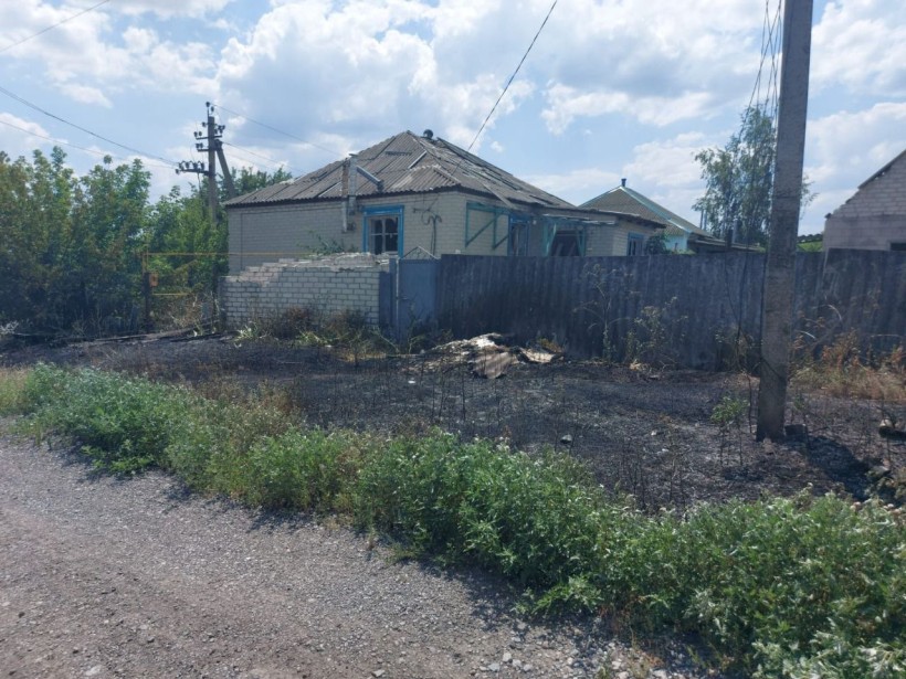Пошкоджений будинок та трава, яка згоріла поруч через ворожий обстріл.