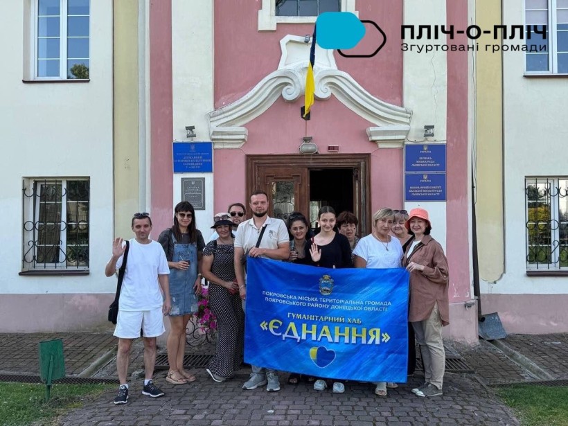 Група переселенців тримає прапор "Гуманітарний хаб "Єднання"