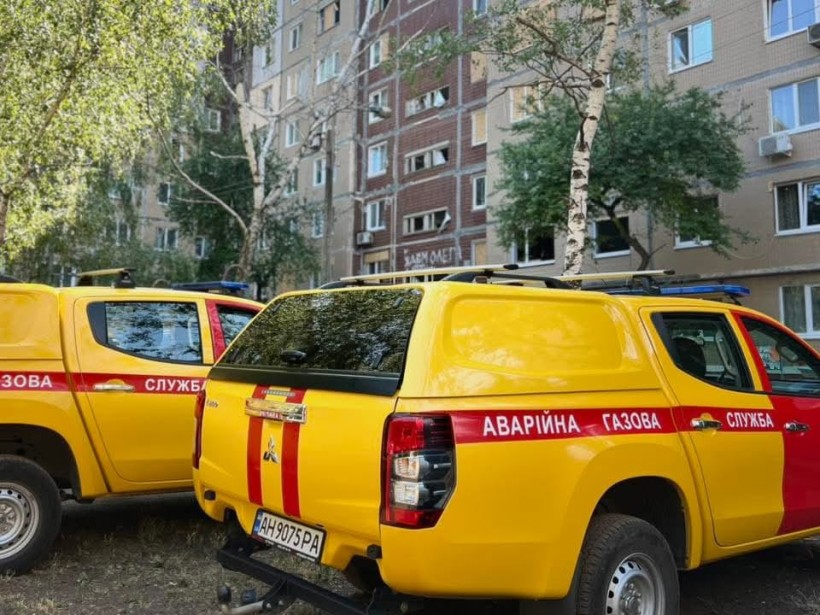 Жовті аварійні газові сервісні вантажівки, припарковані біля багатоповерхового житлового будинку, оточеного деревами, передають відчуття терміновості та готовності.