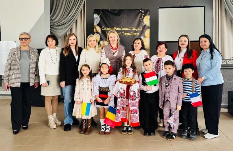 Спільне фото. Представники громад та дітей. Дівчина у національному вбранні тримає на рушнику паляницю.