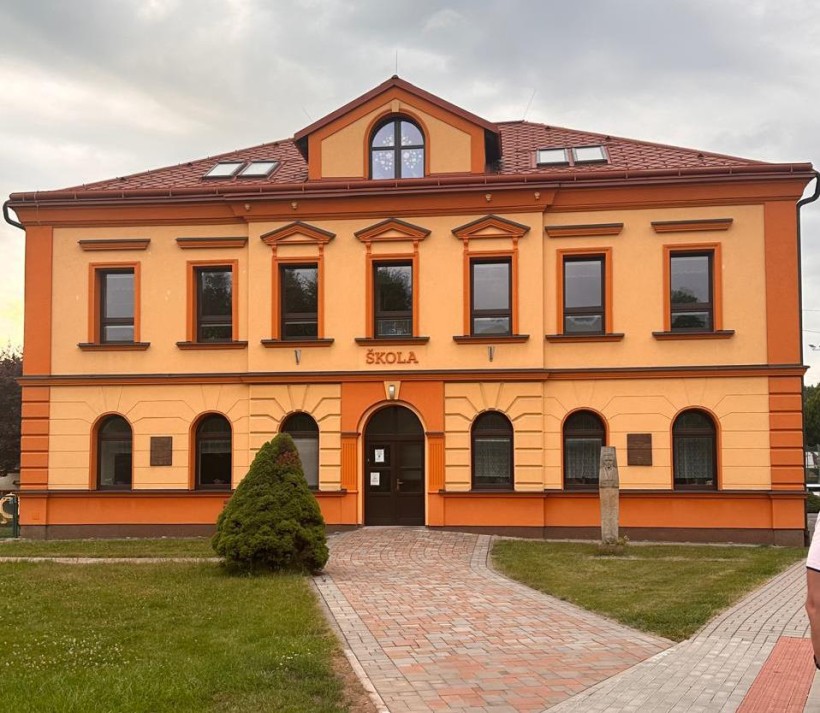 Чеська школа. Двоповерховий будинок, біля якого кам'яні доріжки та декоративні дерева.