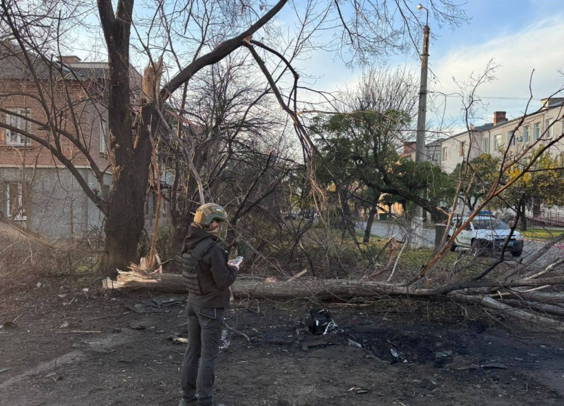 Правоохоронець стоїть біля пошкодженої будівлі та пошкодженого дерева
