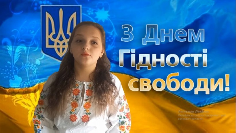 Дівчина, учасниця флешмобу, у вишиванці на тлі українського Прапора та Тризуба.
