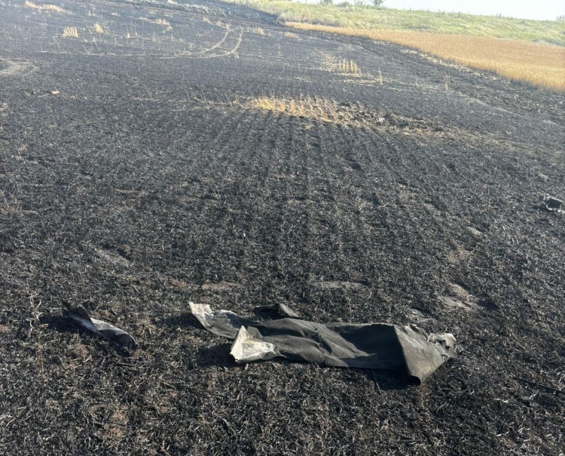 Згоріле поле, майже все чорного кольору. На полі лежать залишки вибухонебезпечних предметів