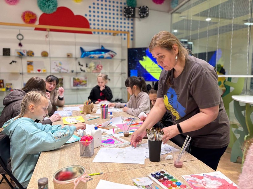 Діти за столом під час малювання під керівництвом наставниці
