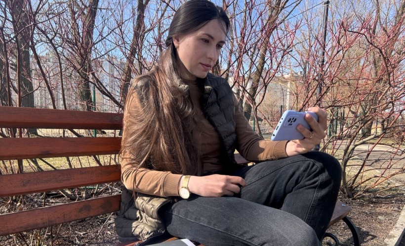 Учасниця заходу з телефоном спілкується з іншими учасниками