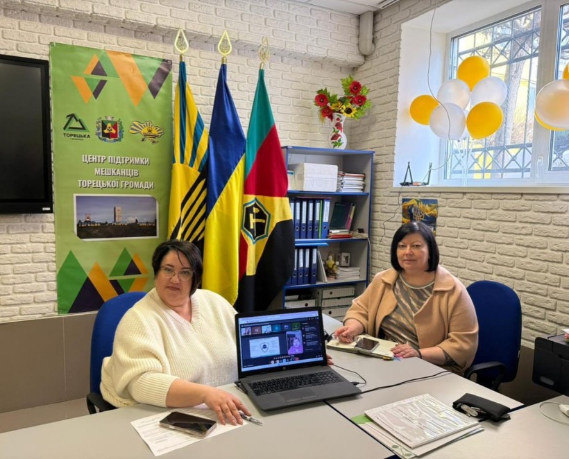 Представники військової адміністрації сидять за столом та слухають доповідача на семінарі