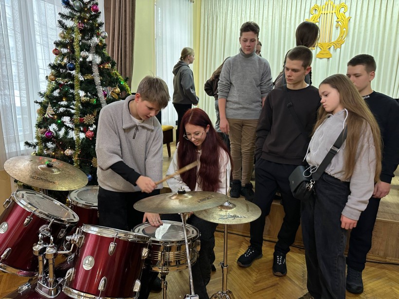 Майстер-клас з гри на ударних інструментах.  Діти сидять біля барабанів та тримають палиці у руках.