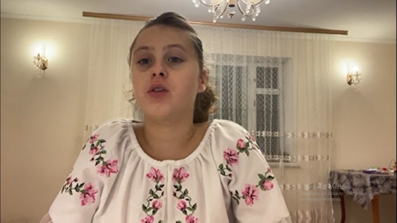 Учасниця конкурсу  у білій вишиванці з рожевою квітковою вишивкою декламує вірш