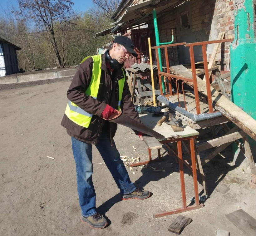 Чоловік пиляє дошку