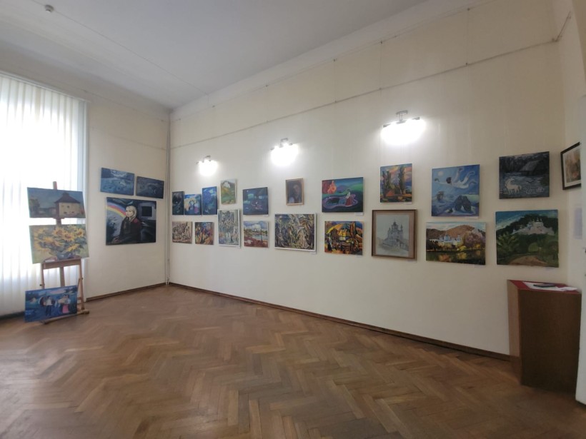Кут світлої виставкової зали з картинами на стінах і біля вікна