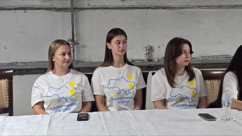 Представниці молодіжної ради Донеччини. Молоді дівчата у білих футболках, уважно дивляться в бік.