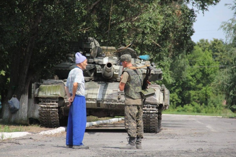 Військовий та цивільний спілкуються біля танку.