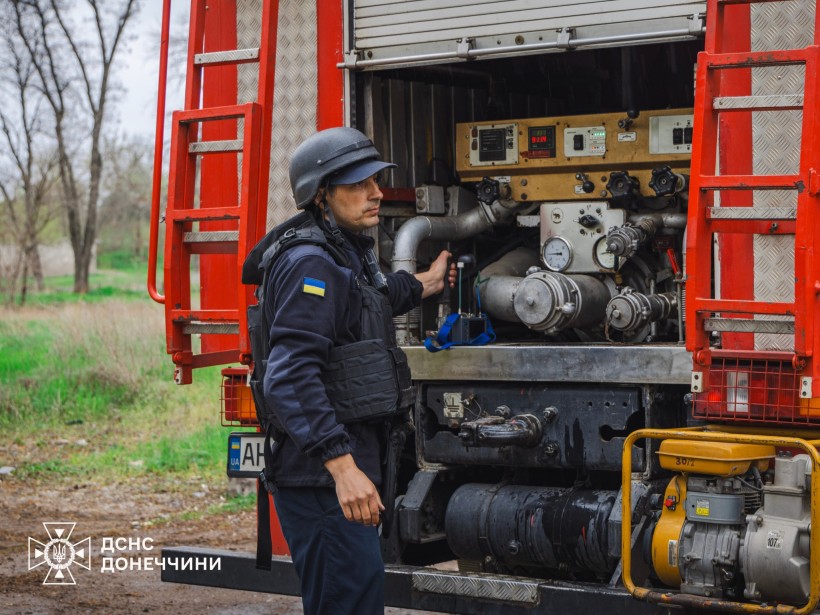 Рятувальник біля пожежної машини дістає гідрант.