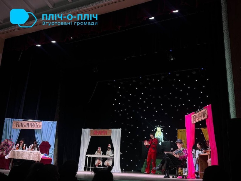 Дія на сцені. Актори грають казкову сімейну виставу «Пан Шкарпеткос та срібне сузір’я Панчішки». На сцені декорації позаду імітація зоряного неба.