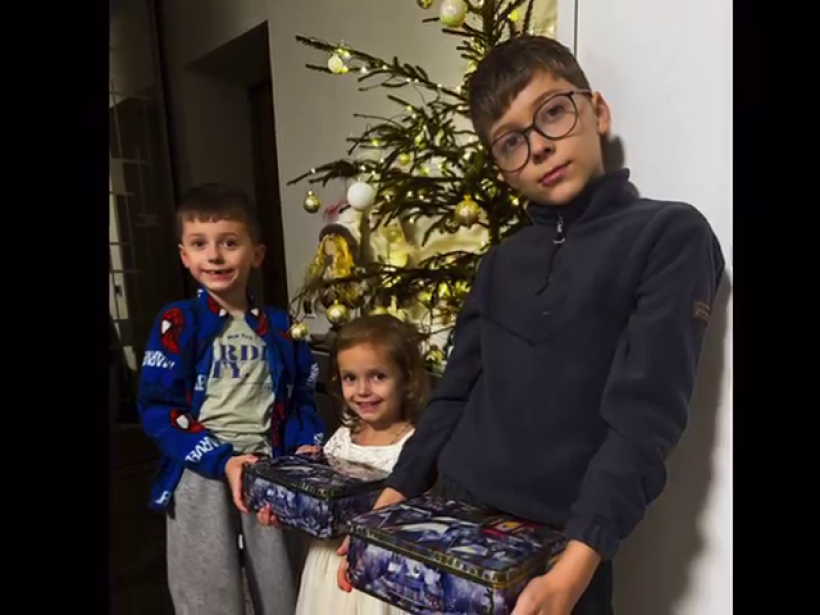 Троє дітей тримають подарунки та посміхаються