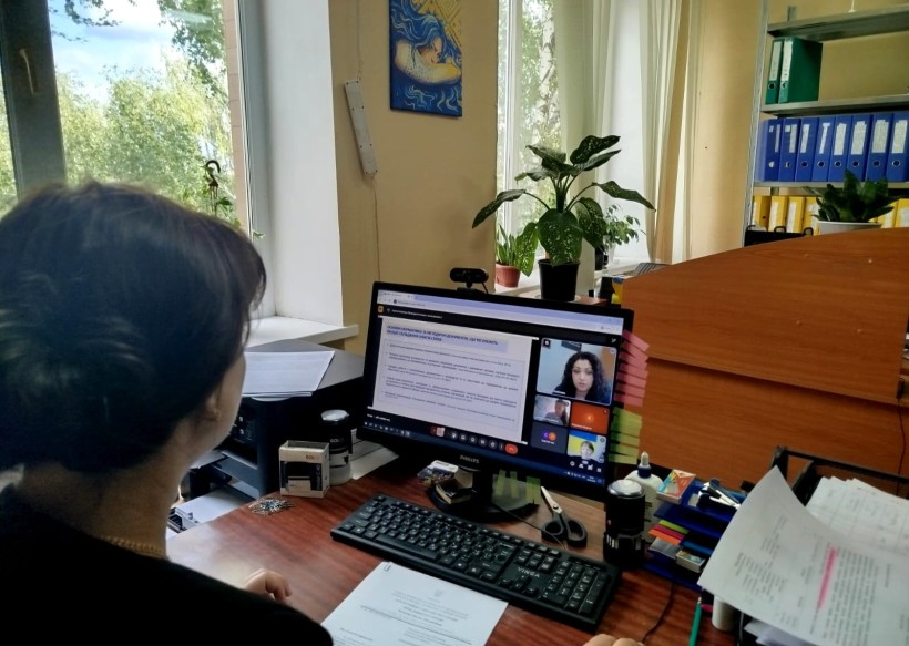 Представник військової адміністрації сидить за столом та слухає доповідача на семінарі