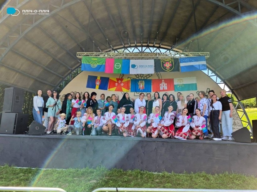 Спільне фото на сцені, яка прикрашена прапорами громад-партнерів Бахмутської громади
